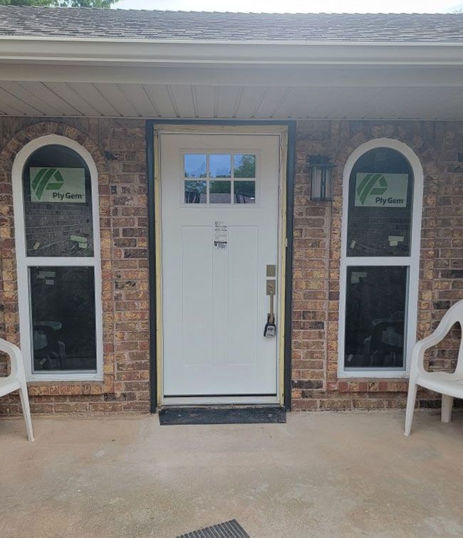 Brick porch with white front door and two arched windows, flanked by white chairs
