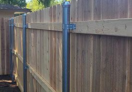 Wooden backyard fence with metal posts and horizontal rails beside a gate and shed.