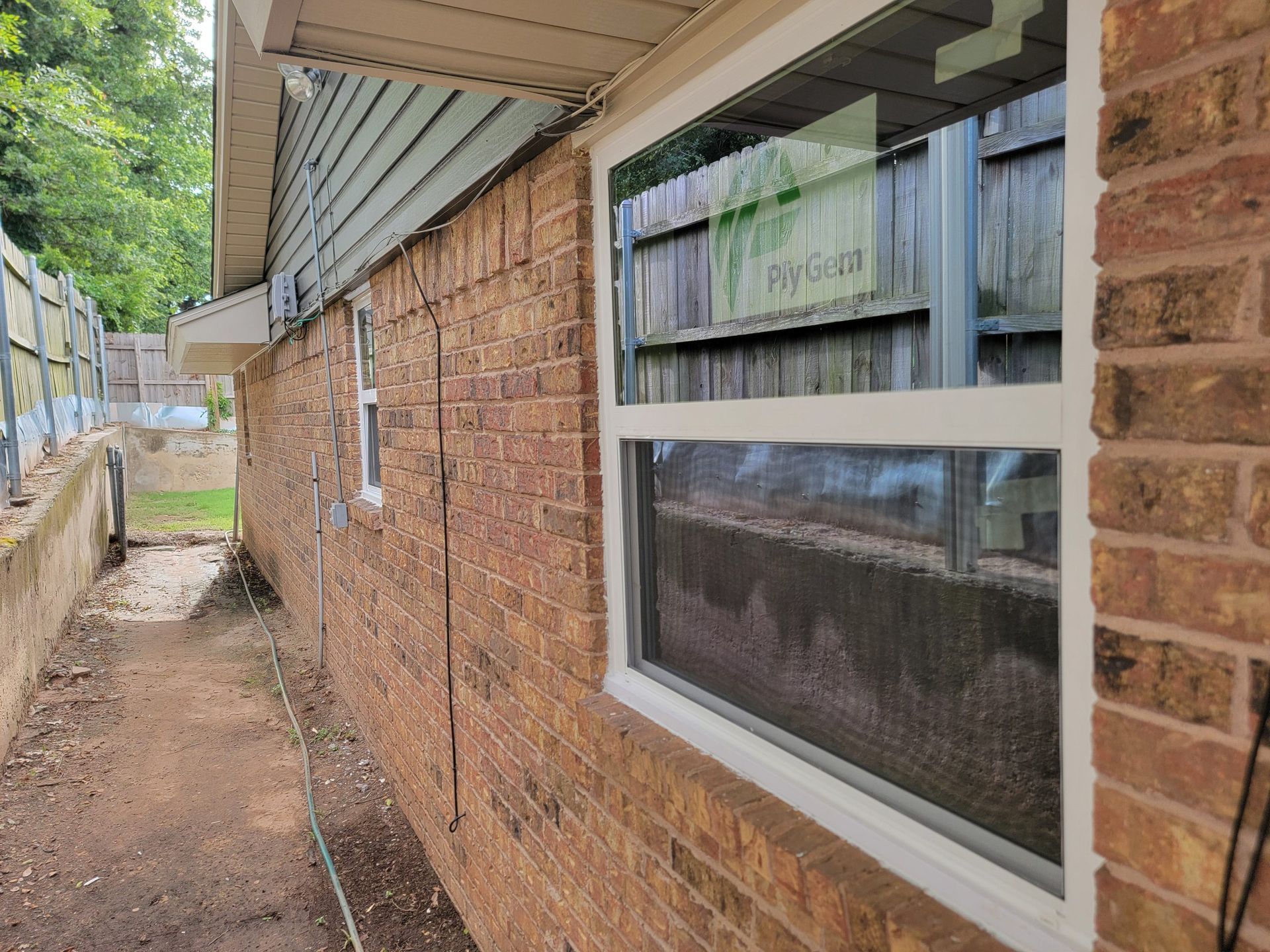 Brick house exterior with a narrow side walkway and a white-trimmed window under the eaves