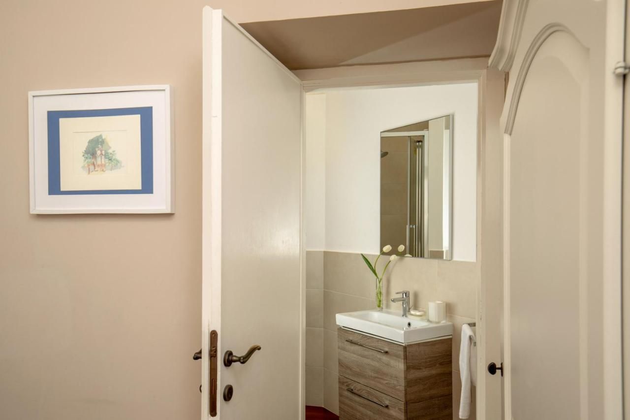 a bathroom with a washbasin and mirror and a painting above the door