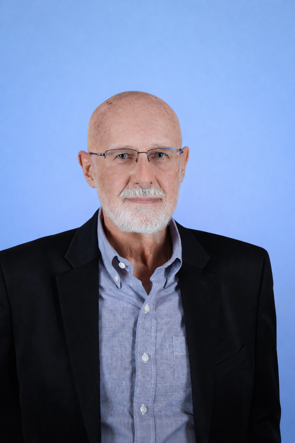 Woman smiling, wearing a black blazer over a red top. Dark, wavy hair. White background.