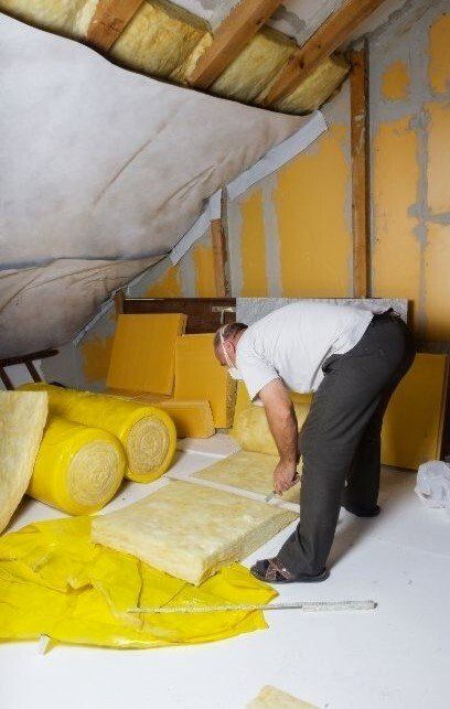 handyman cutting insulation in the attic