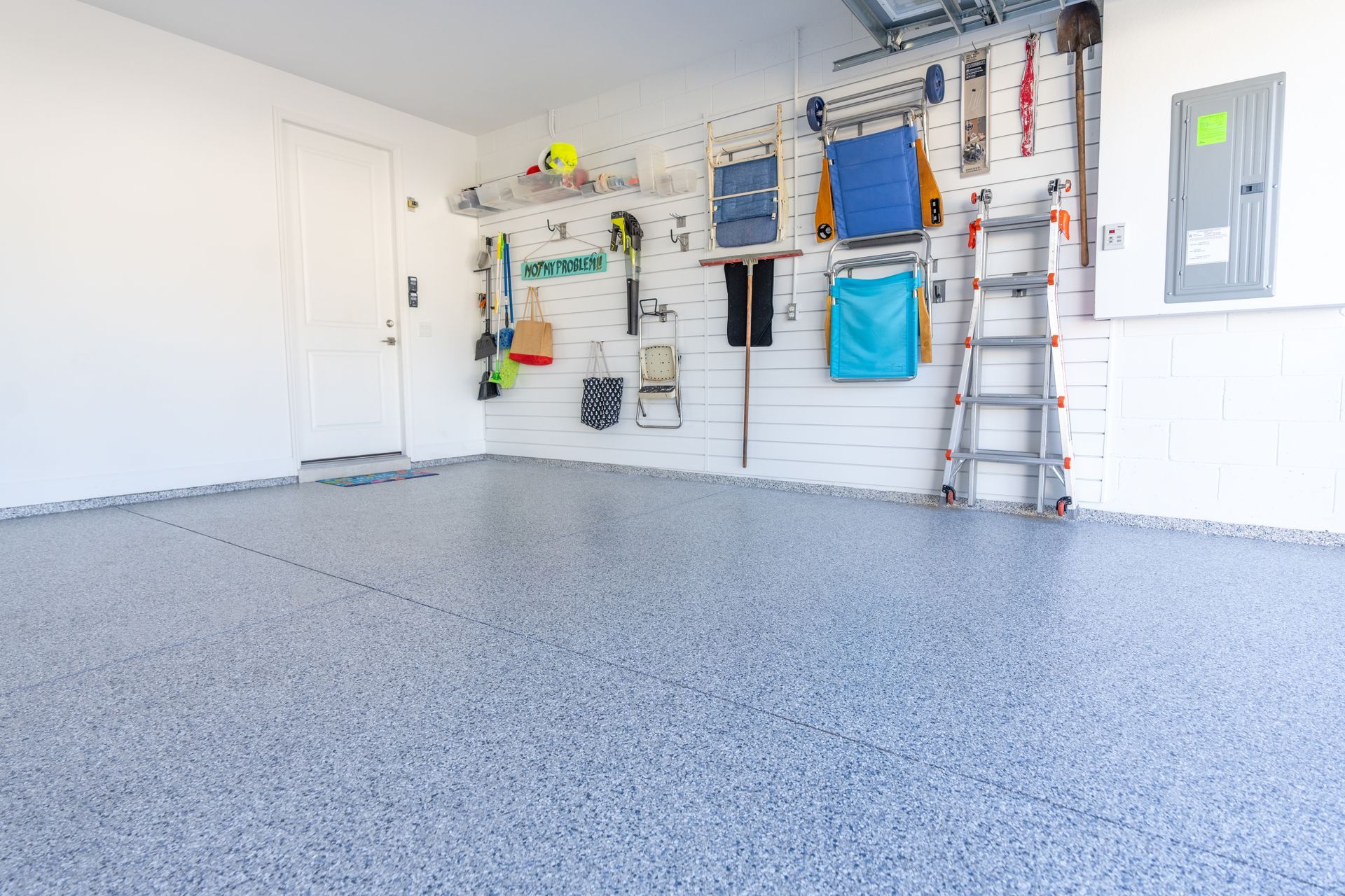 Garage interior with epoxy floor and tools organized on a white pegboard wall.