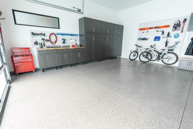 Spacious garage with gray epoxy floor, dark gray cabinets, bikes, tools, and red toolbox.