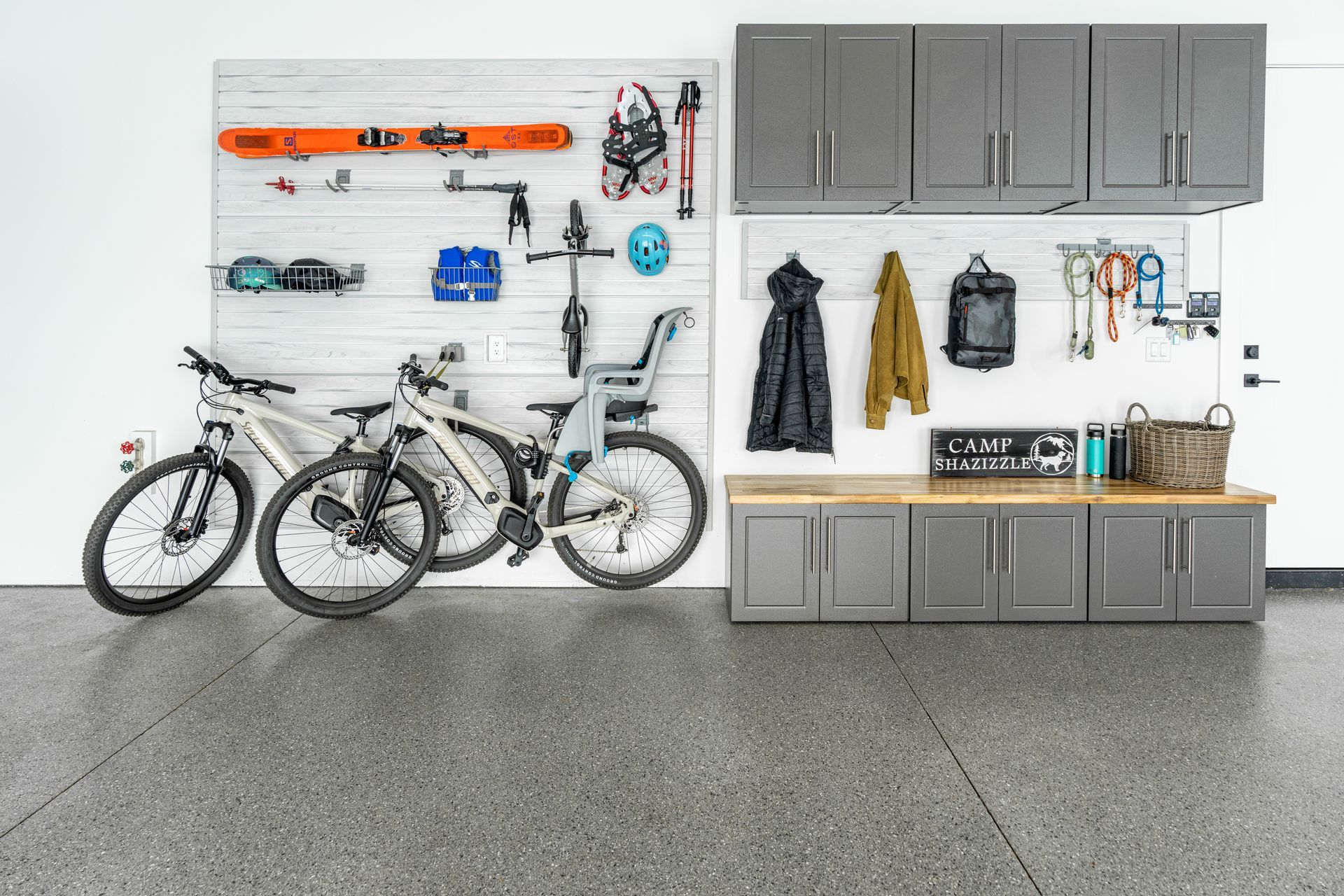 Garage with storage cabinets, bikes, and gear organized on a wall. Gray and wood tones.