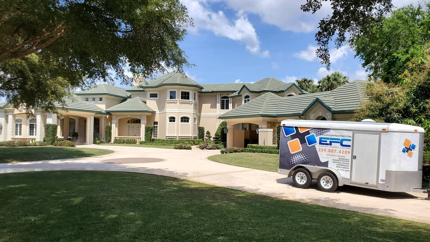 Large beige house with green roof, trailer in the driveway.
