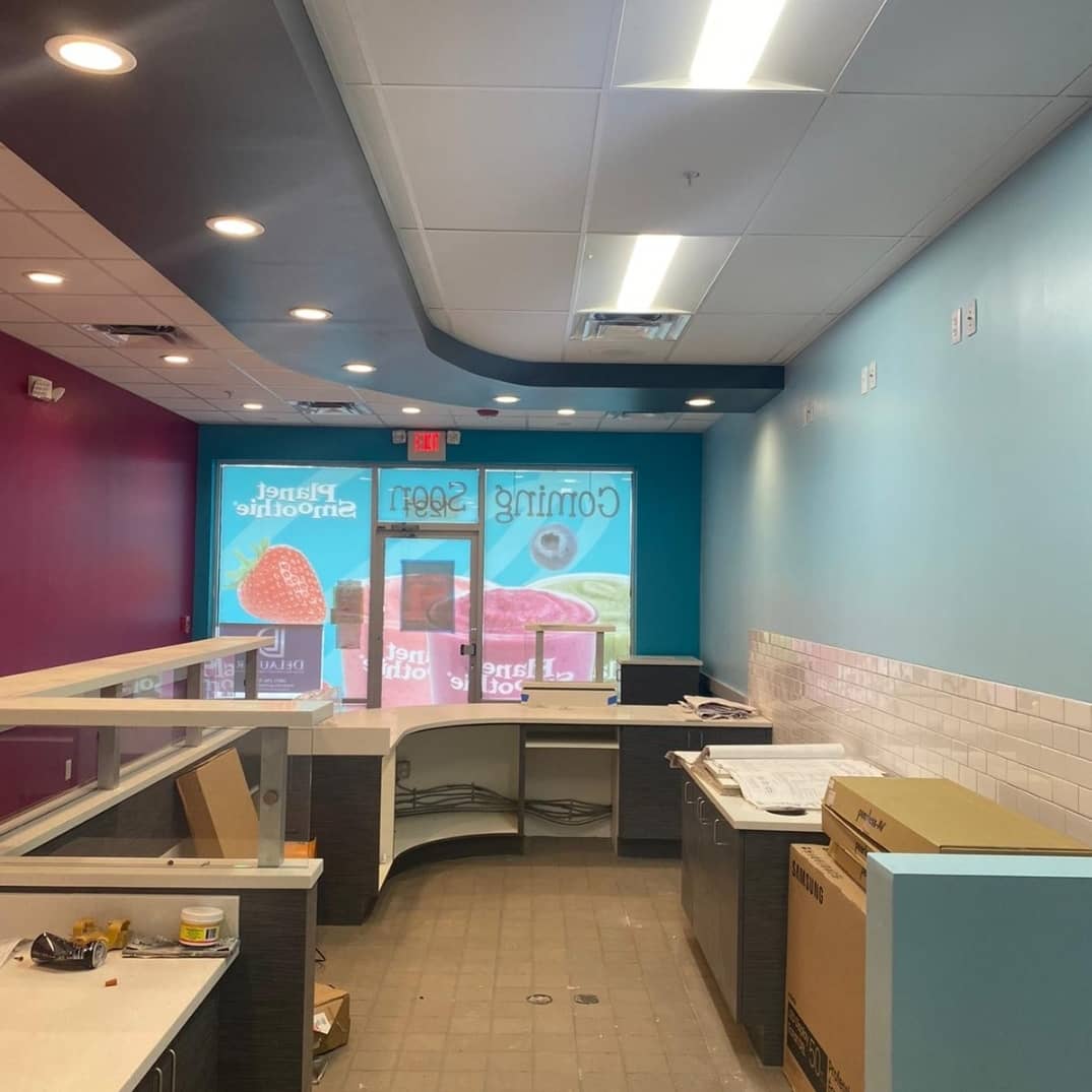 Interior of a commercial space under renovation with countertops, colorful walls, and an exit sign.