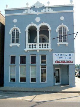 Two-story blue building with white arched balcony and windows; Varnado Law Firm sign.