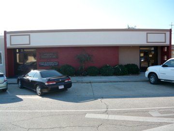 Building exterior with parked cars; red and tan facade, large windows.
