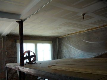Interior construction: a loft with exposed brick, a ceiling with drywall, and a support beam.