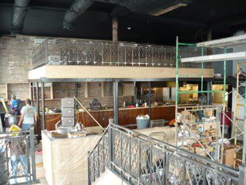 Restaurant under construction; balcony with ornate railing. Workers in various stages, tools, and materials visible.