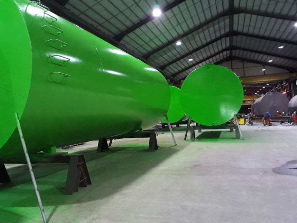 Large, bright green tanks in an indoor facility.