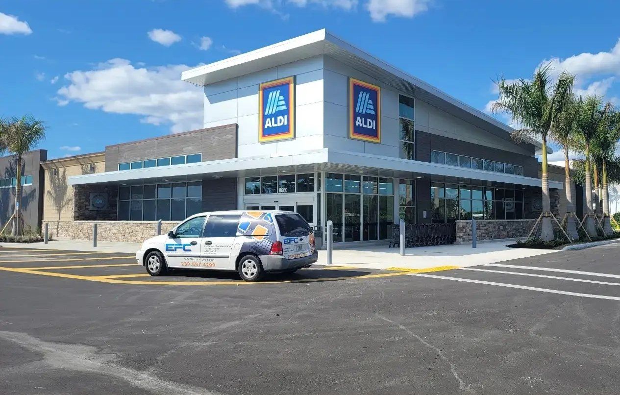 Exterior of an Aldi grocery store on a sunny day, with a vehicle parked in front.