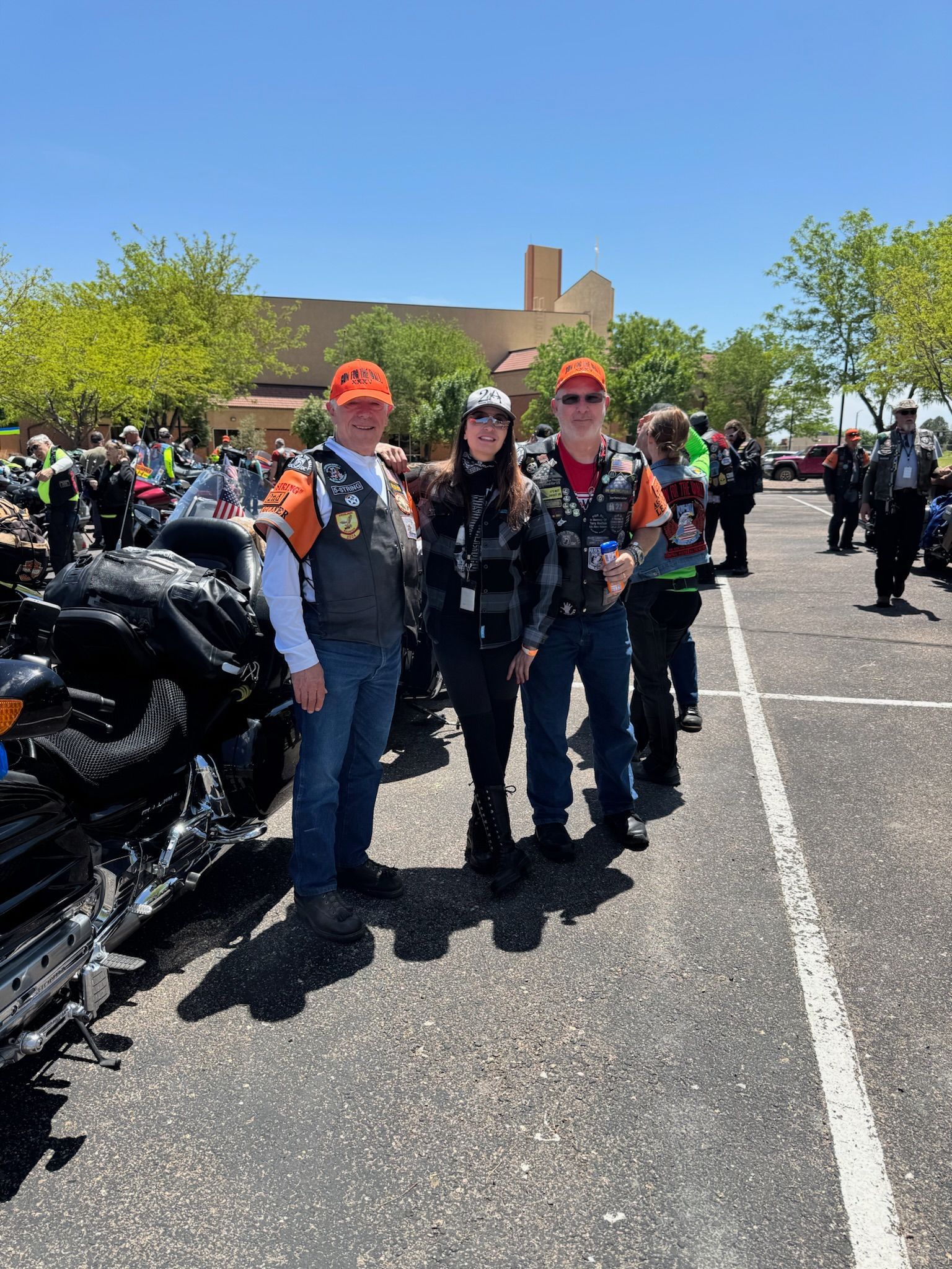 A group of people standing next to a motorcycle in a parking lot.