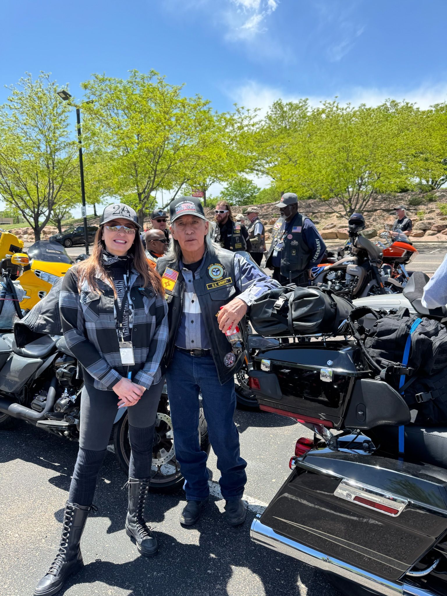 A man and a woman are standing next to motorcycles in a parking lot.