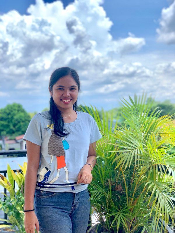 Loraine, Marketing & Engagement Strategist at Avenir Consulting, smiling outdoors near tropical plants.