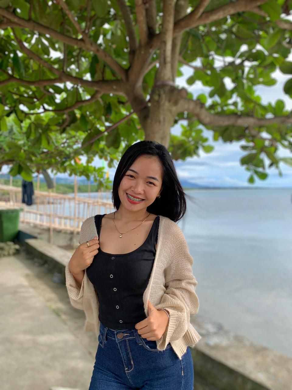 Rocille, Junior Admin at Avenir Consulting, smiling under a tree near the waterfront.