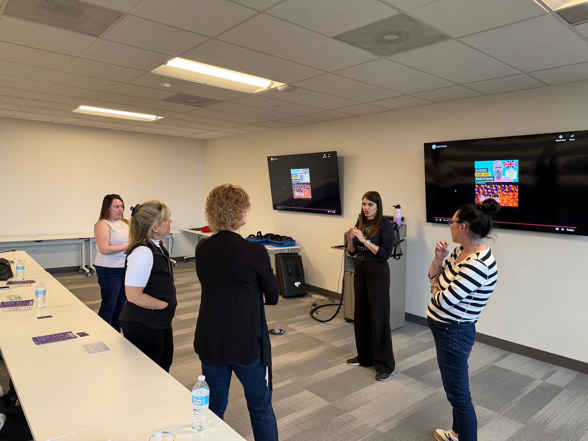 A group of women are standing in a room talking to each other.