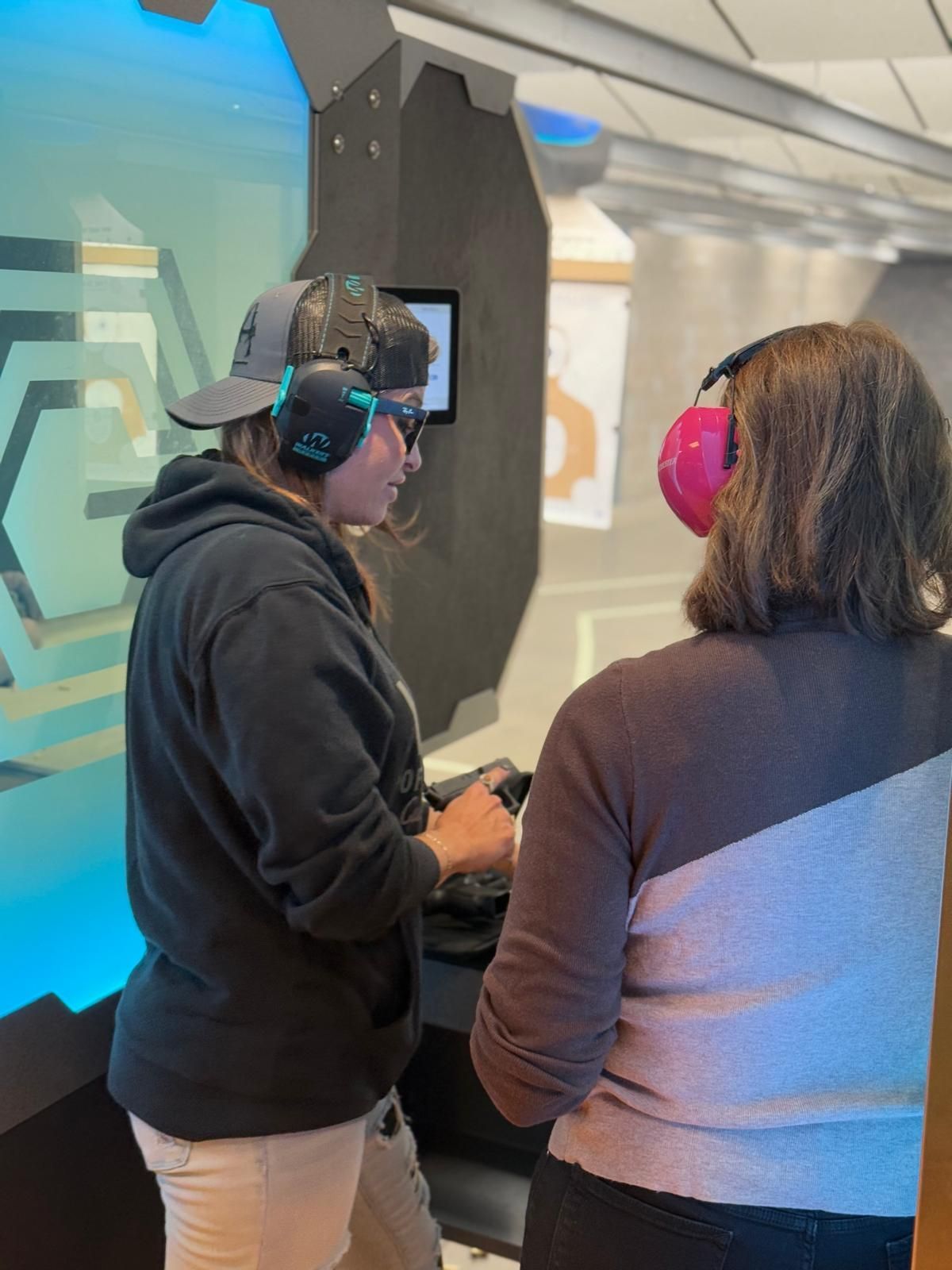 Avenir Consulting instructor guiding a student on firearm handling at a training booth.
