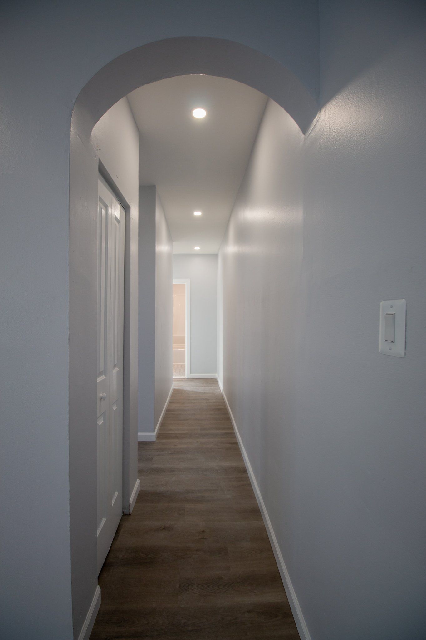 Unit hallway with round arch and grey flooring