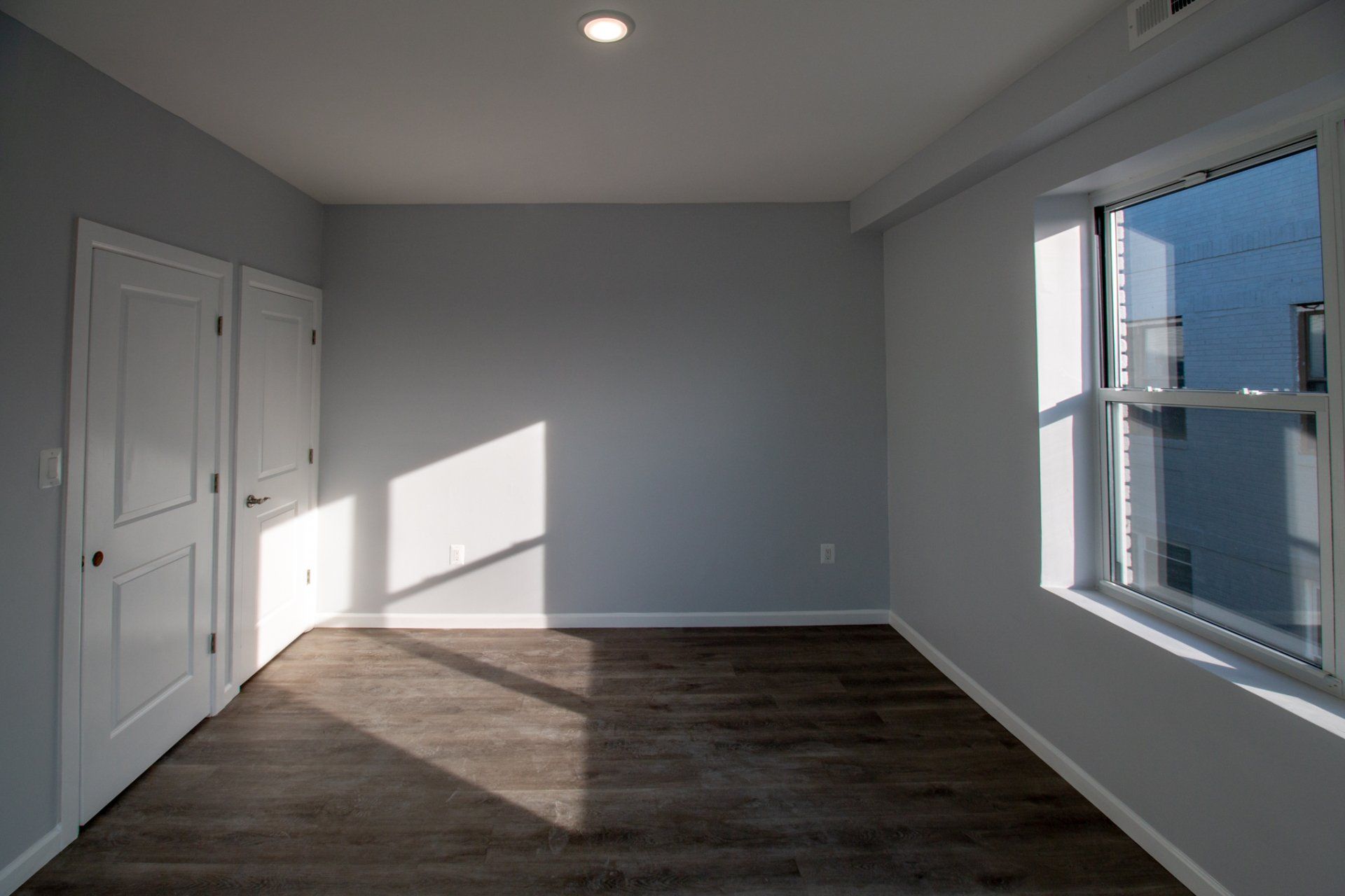 Updated bedroom with grey flooring and window.