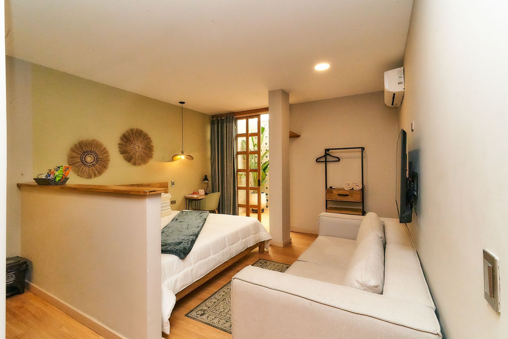 Acogedora habitación de hotel con cama, sofá y puerta abierta a una zona al aire libre.