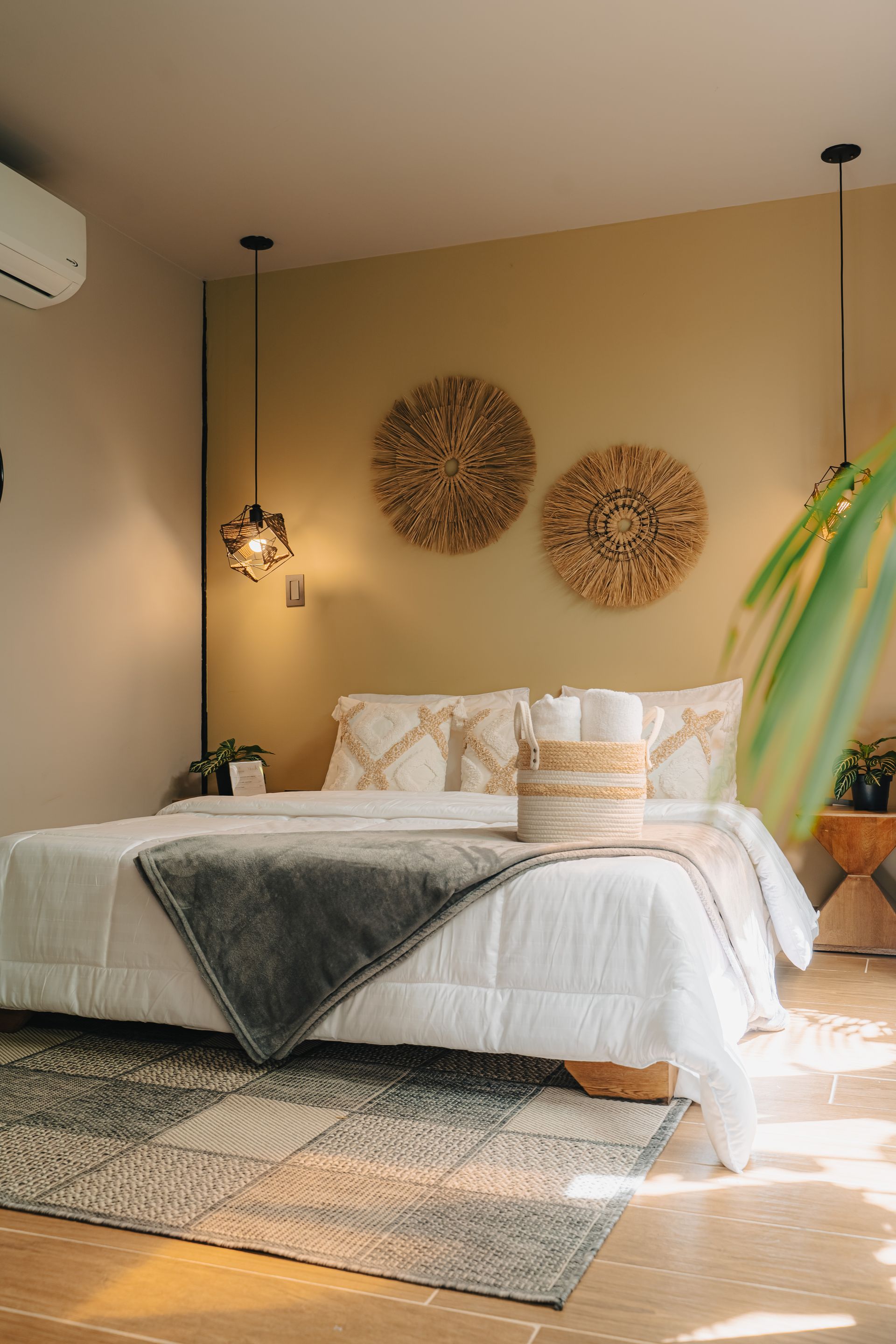 Dormitorio con cama, lámparas colgantes, decoración de pared tejida y una alfombra estampada.