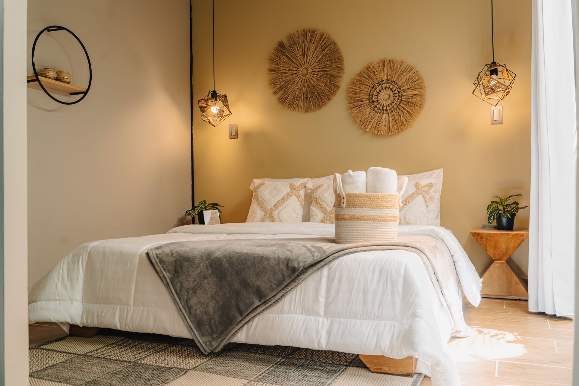 Dormitorio con cama blanca, paredes beige y arte decorativo tejido en la pared.