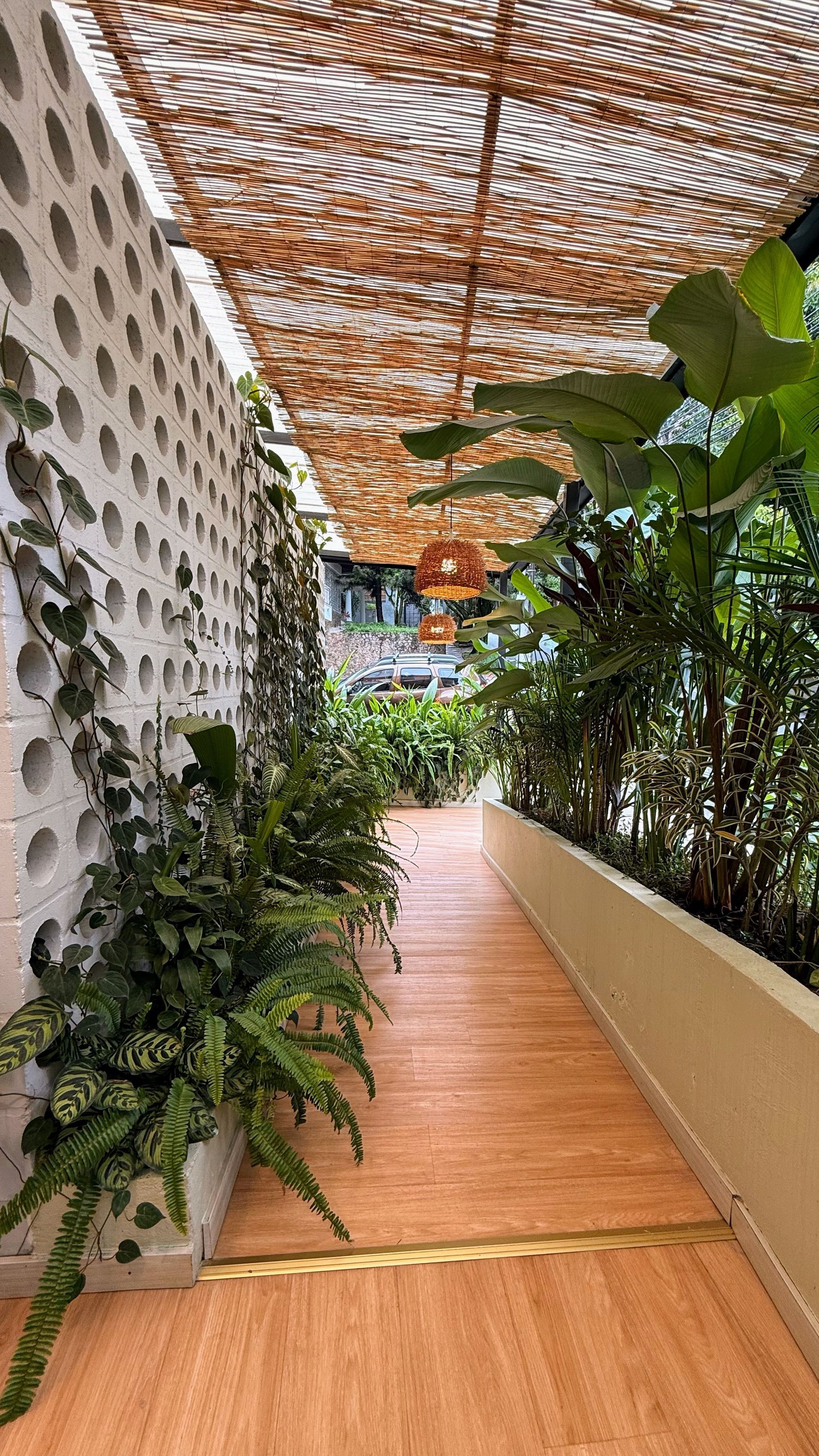 Sendero con suelo imitación madera, pared blanca con estampado vegetal y cubierta tejida. 