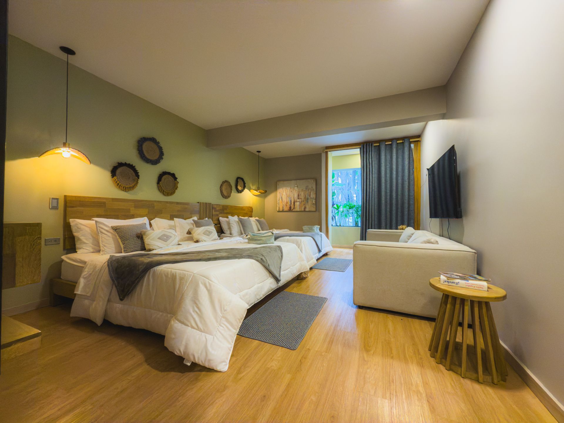 Habitación de hotel con dos camas, un pequeño sofá, TV y arte decorativo en la pared.