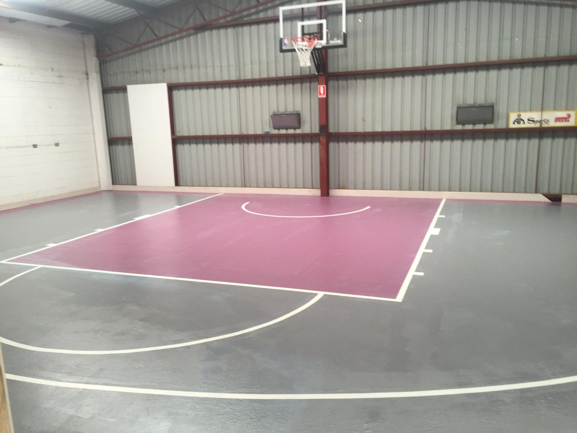 A basketball court in a warehouse with a purple court
