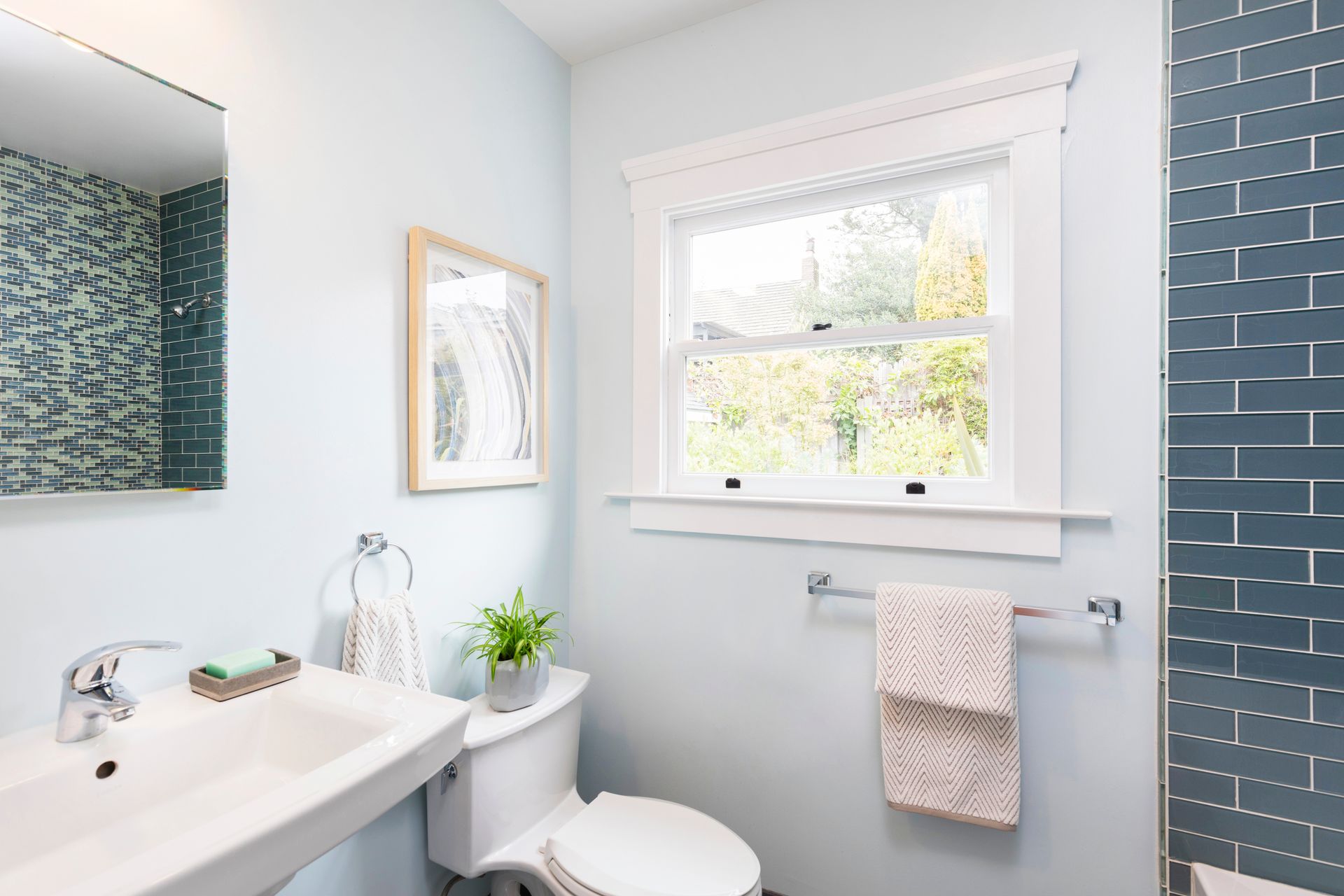 Bathroom with blue walls, window, white sink, toilet, and decorative tile. Bathroom with blue walls, window, white sink, toilet, and decorative tile.
