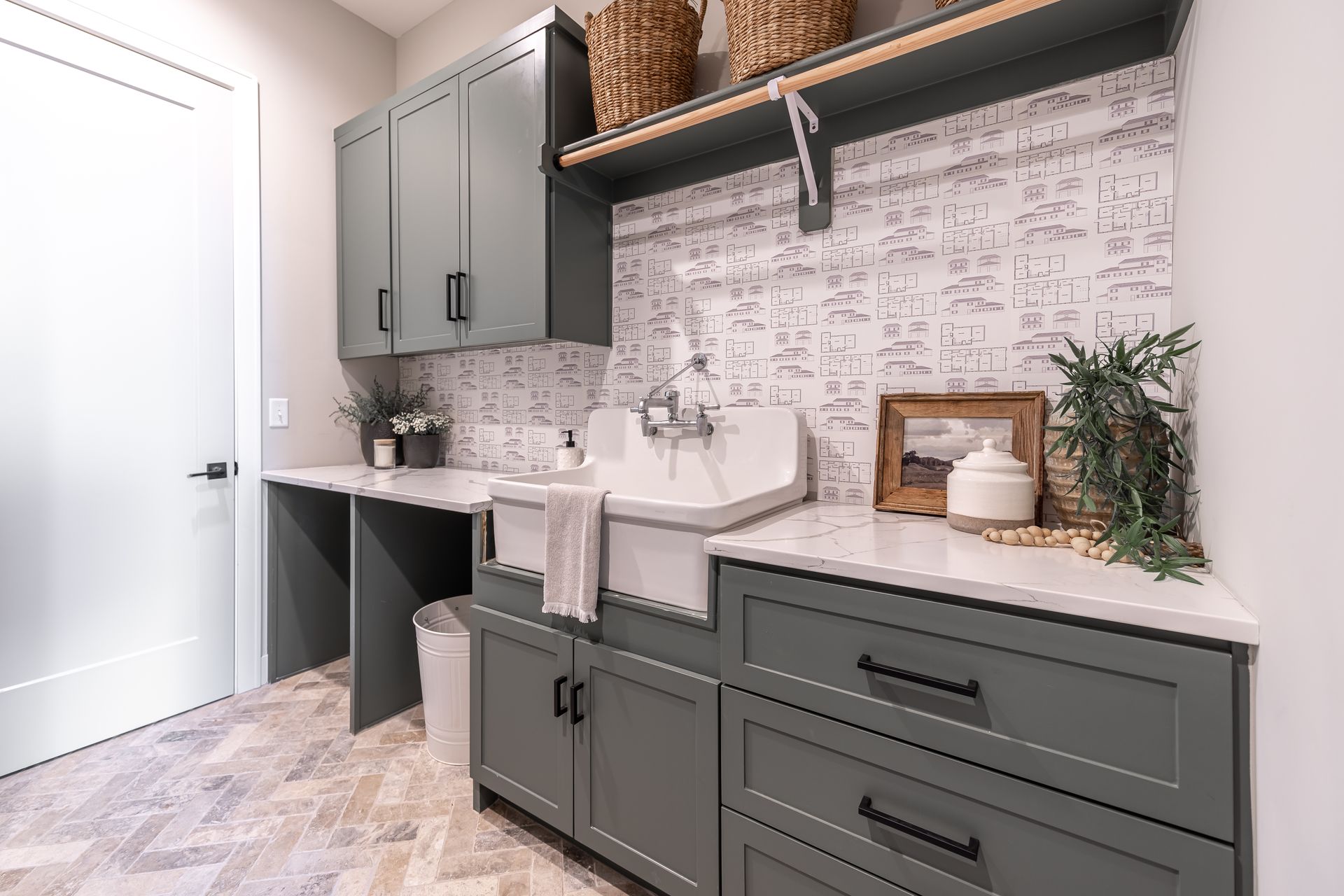 Gray laundry room with cabinetry, sink, and textured backsplash. Baskets on a shelf.