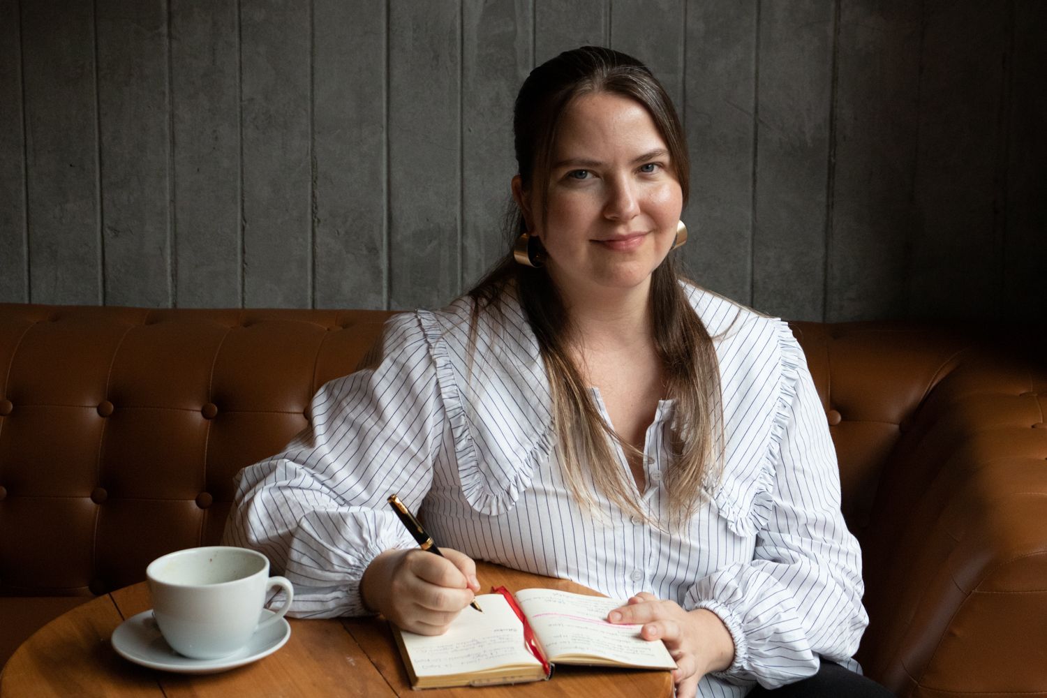 Una mujer con cabello largo lleva un suéter rosa y sonríe.
