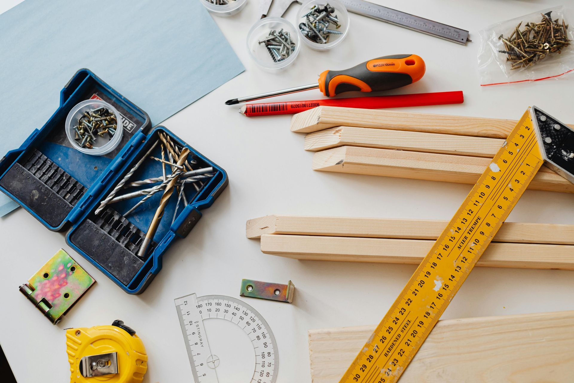 Workbench with tools: drill bits, screws, wood pieces, a ruler, and a tape measure.