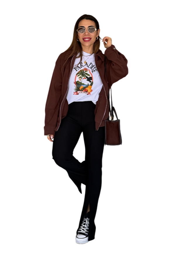 Mujer con chaqueta marrón, camiseta blanca, pantalones negros con aberturas laterales, gafas de sol y bolso.