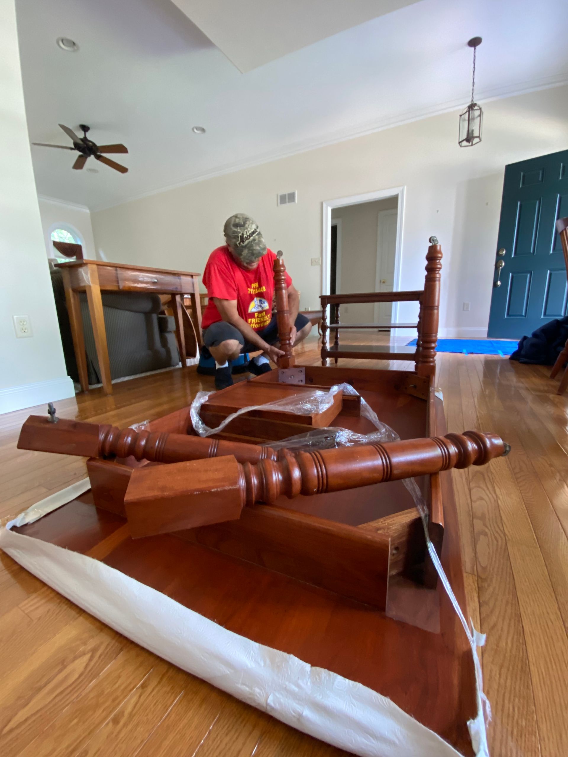 A man is fixing a wooden chair in a living room.