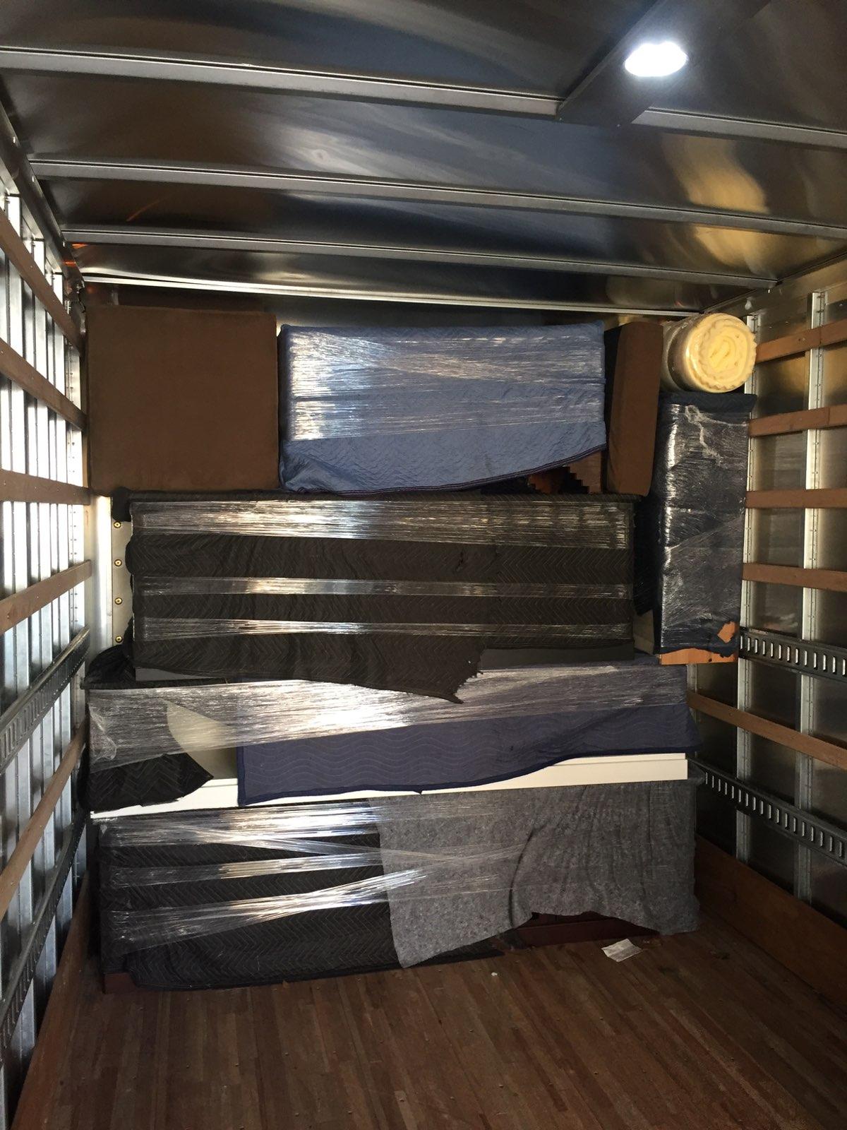 The inside of a moving truck filled with boxes and blankets.