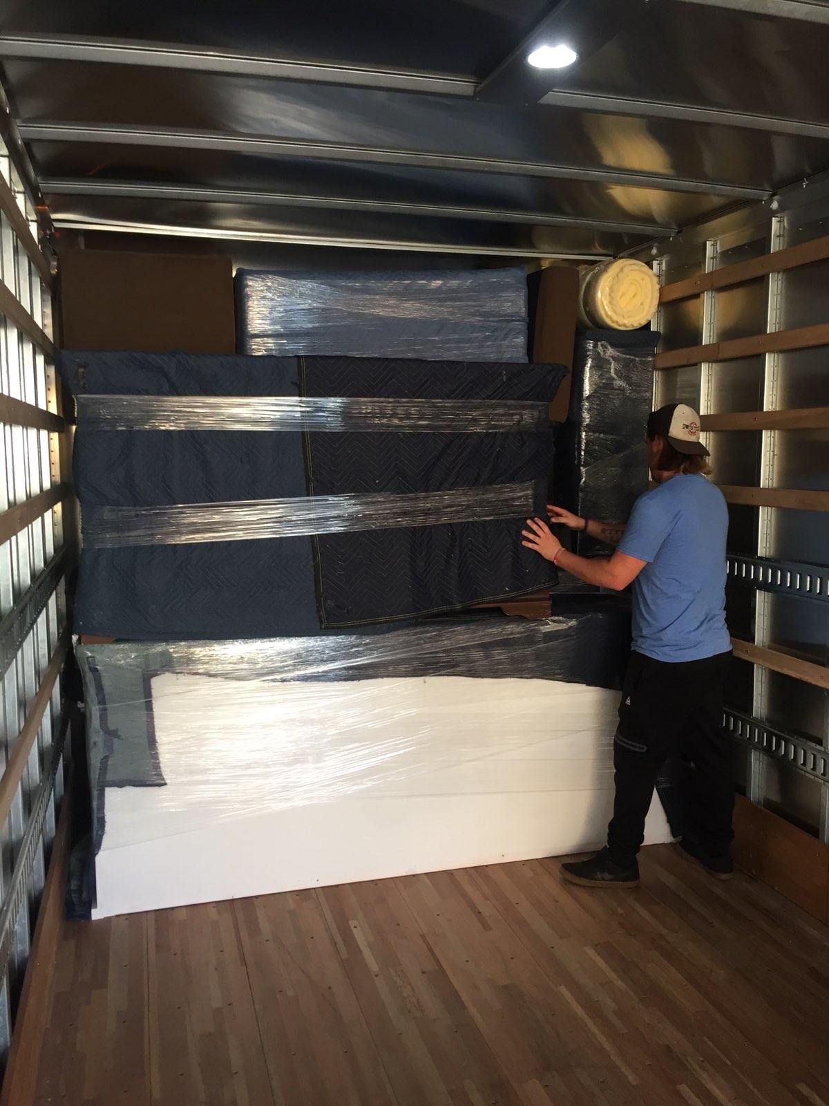 A man is loading a couch into a moving truck.