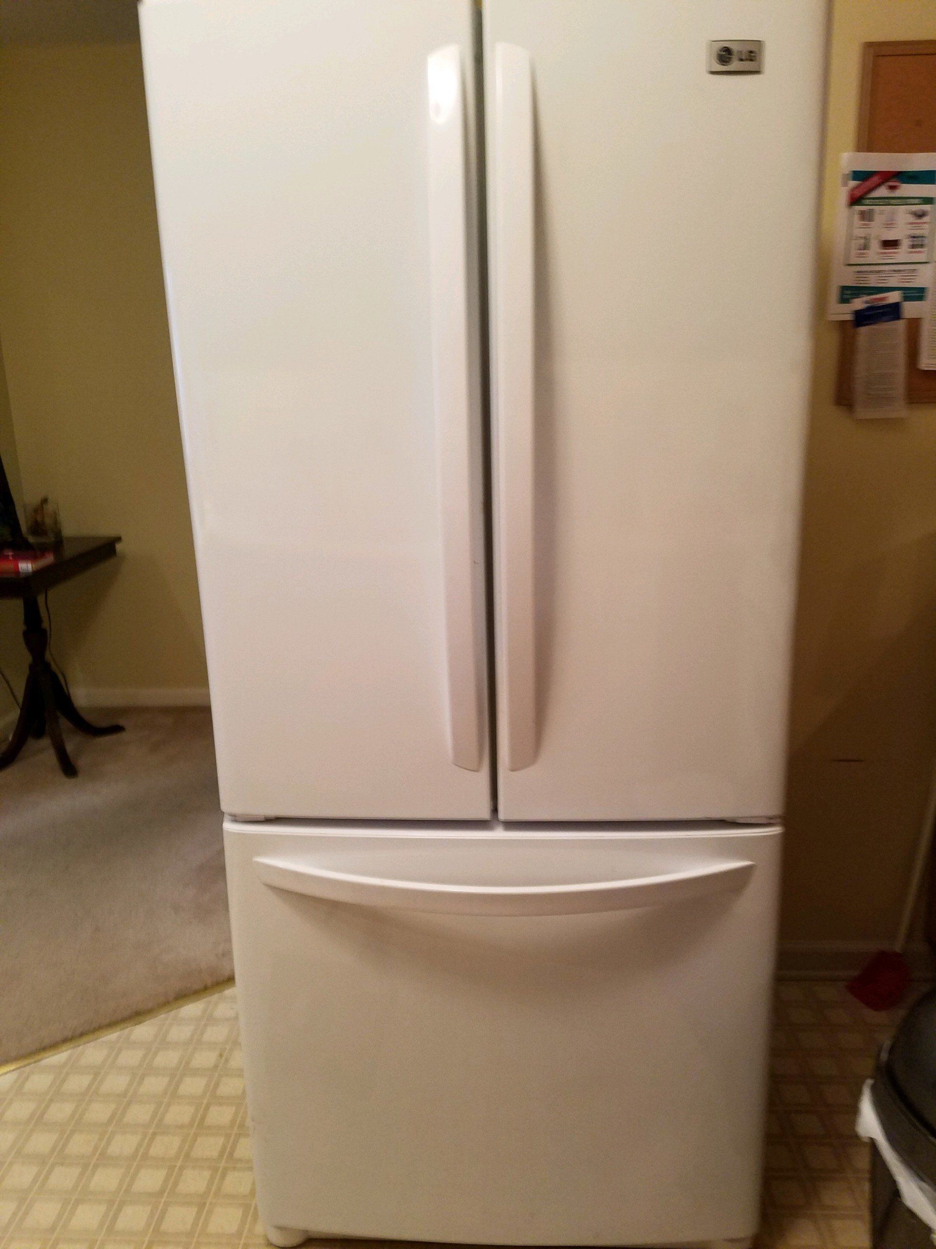 A white refrigerator is sitting on a tiled floor in a kitchen.