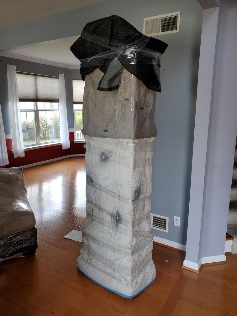 A statue is wrapped in plastic in a living room.