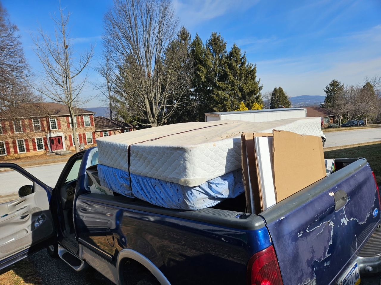 A woman is holding a brown leather couch in a living room.