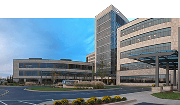 a large building with a lot of windows and a parking lot in front of it .