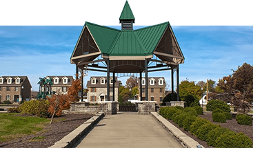 a gazebo with a green roof is in the middle of a park .
