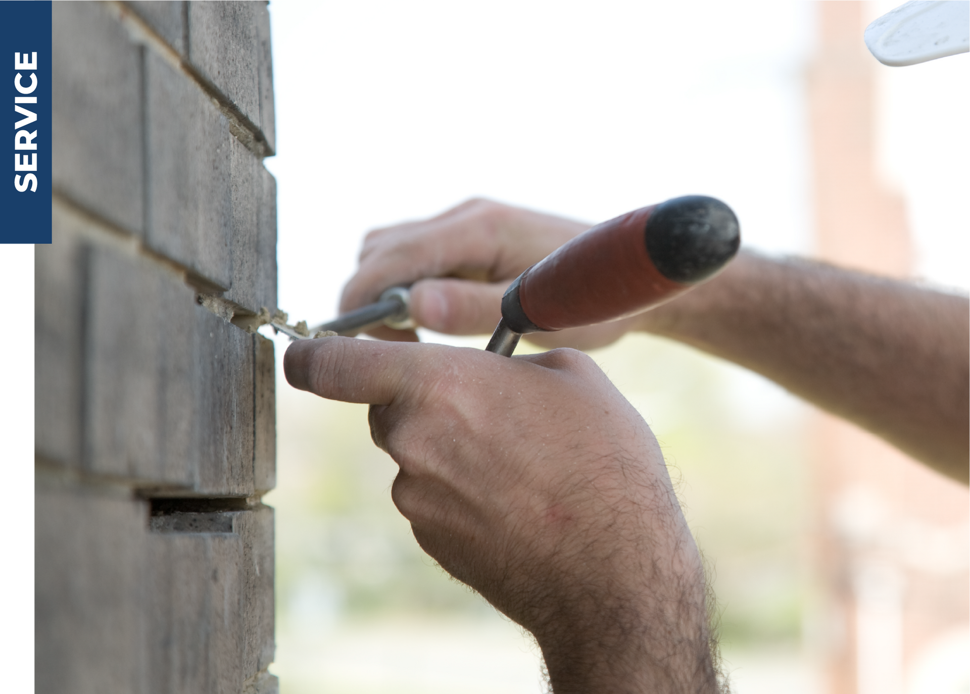 A man is using a screwdriver to fix a hole in a brick wall