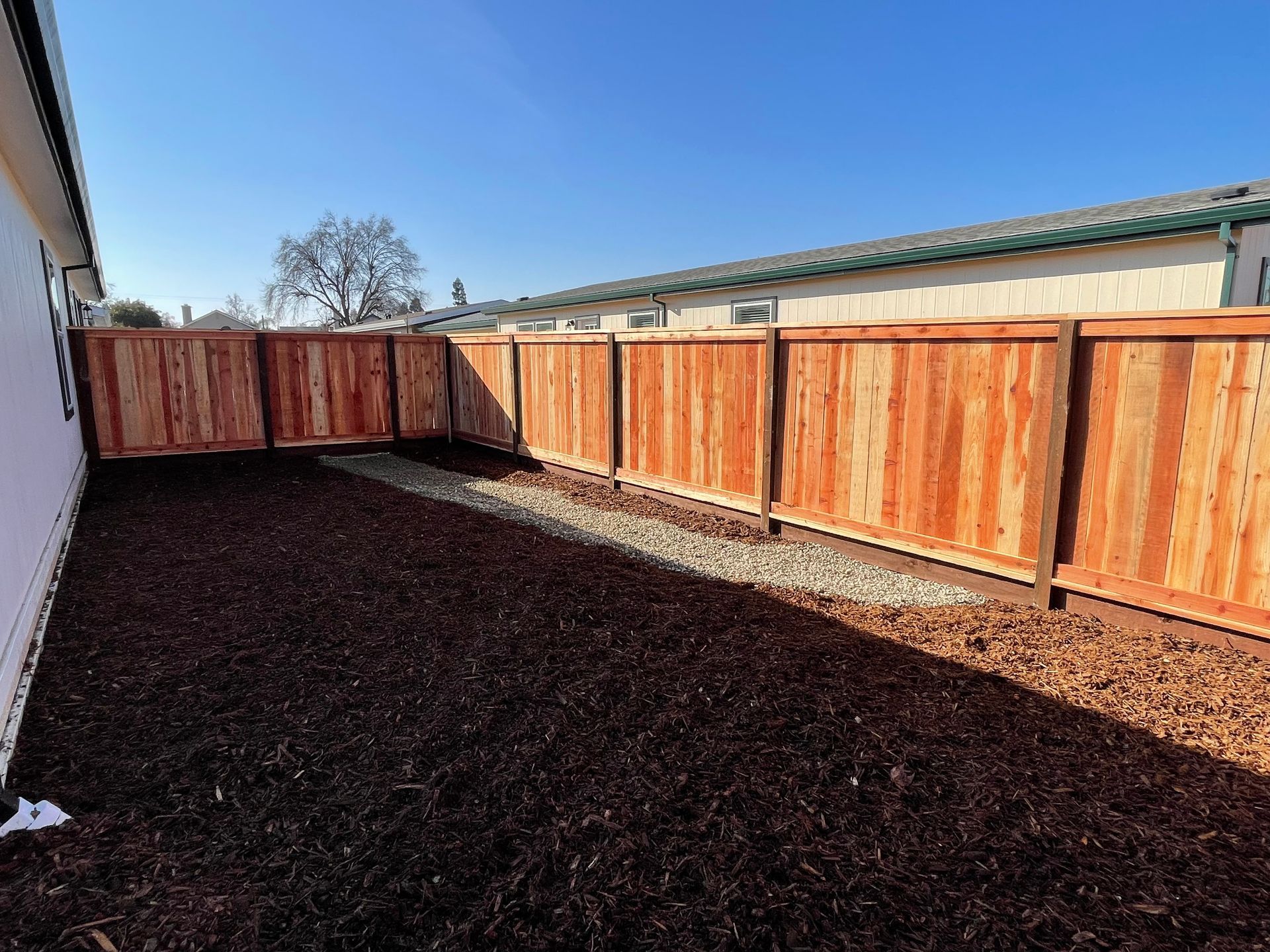 Wooden fence with a framed section, built on a slope with landscaping.