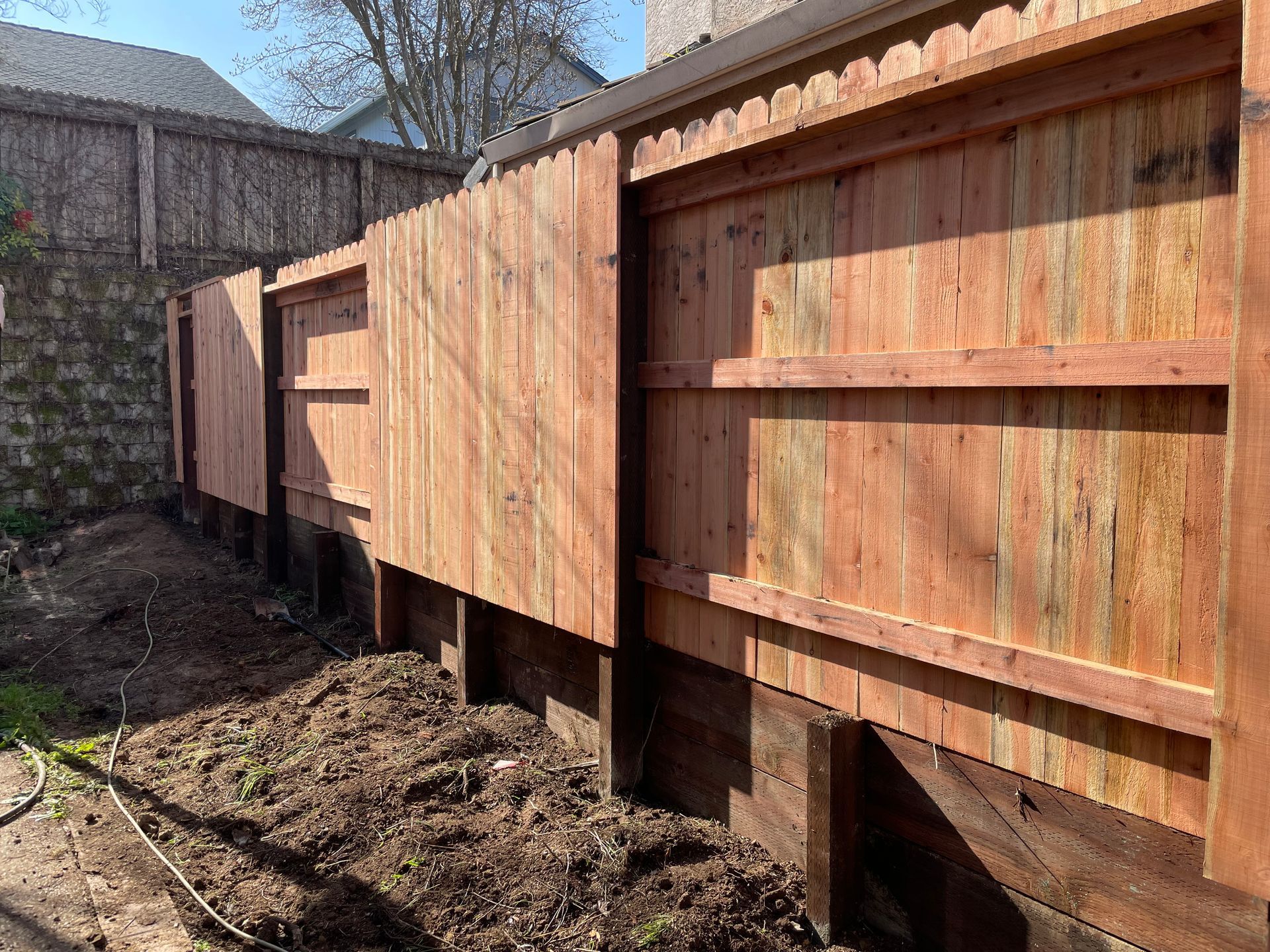 White fenced-in pool area, with clear blue water and diving board. Lattice top fence design.