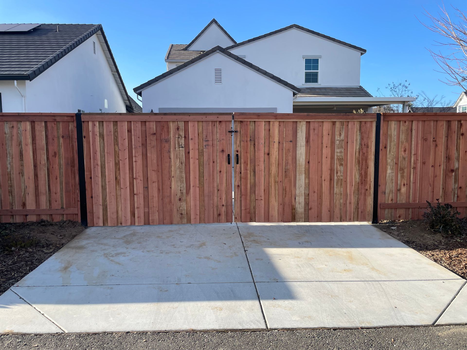 Black metal fence surrounding a blue-water pool, with a gate, patio furniture, and a red umbrella.