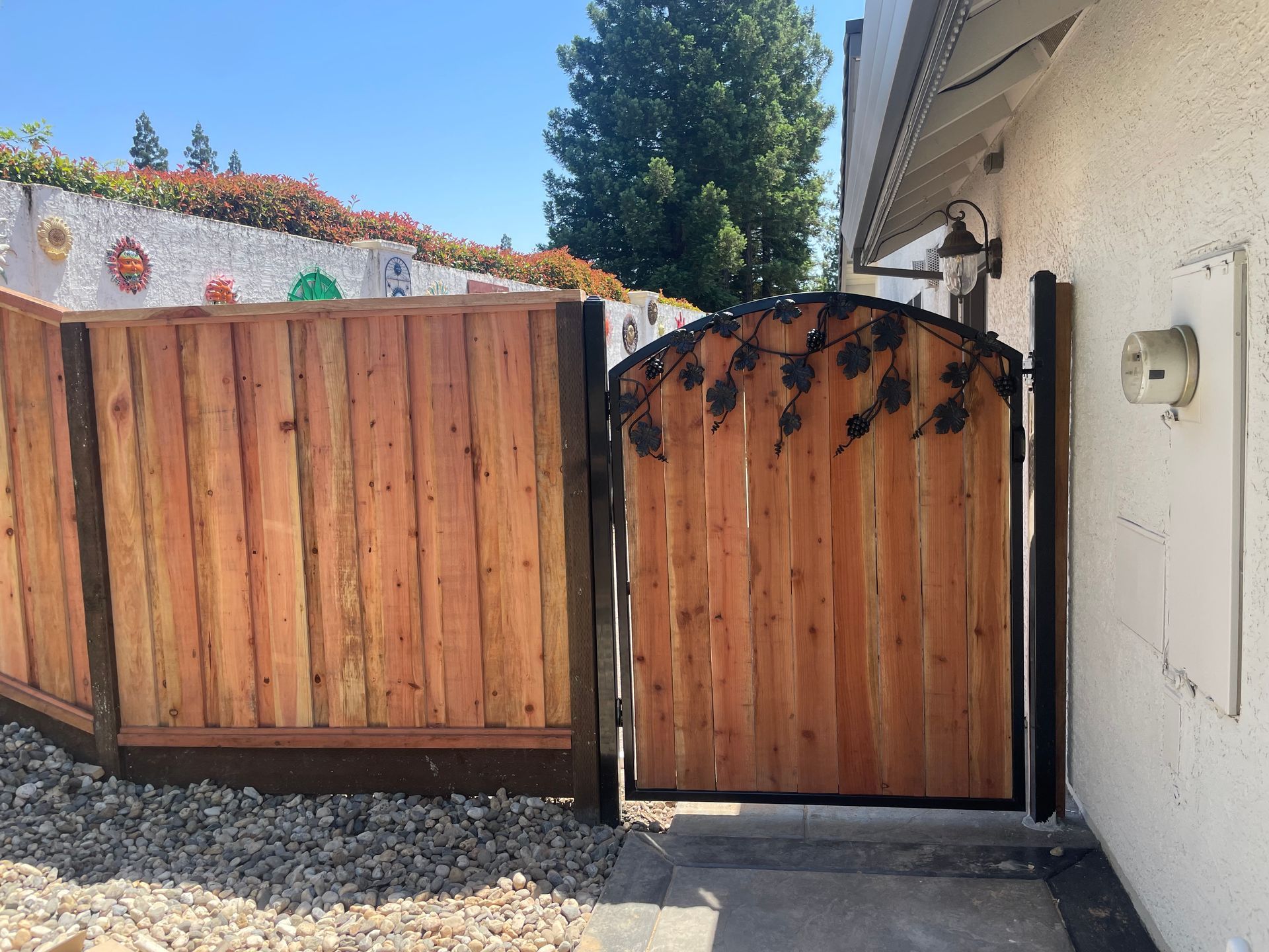 Wooden fence and gate with metal vine details. Exterior view.