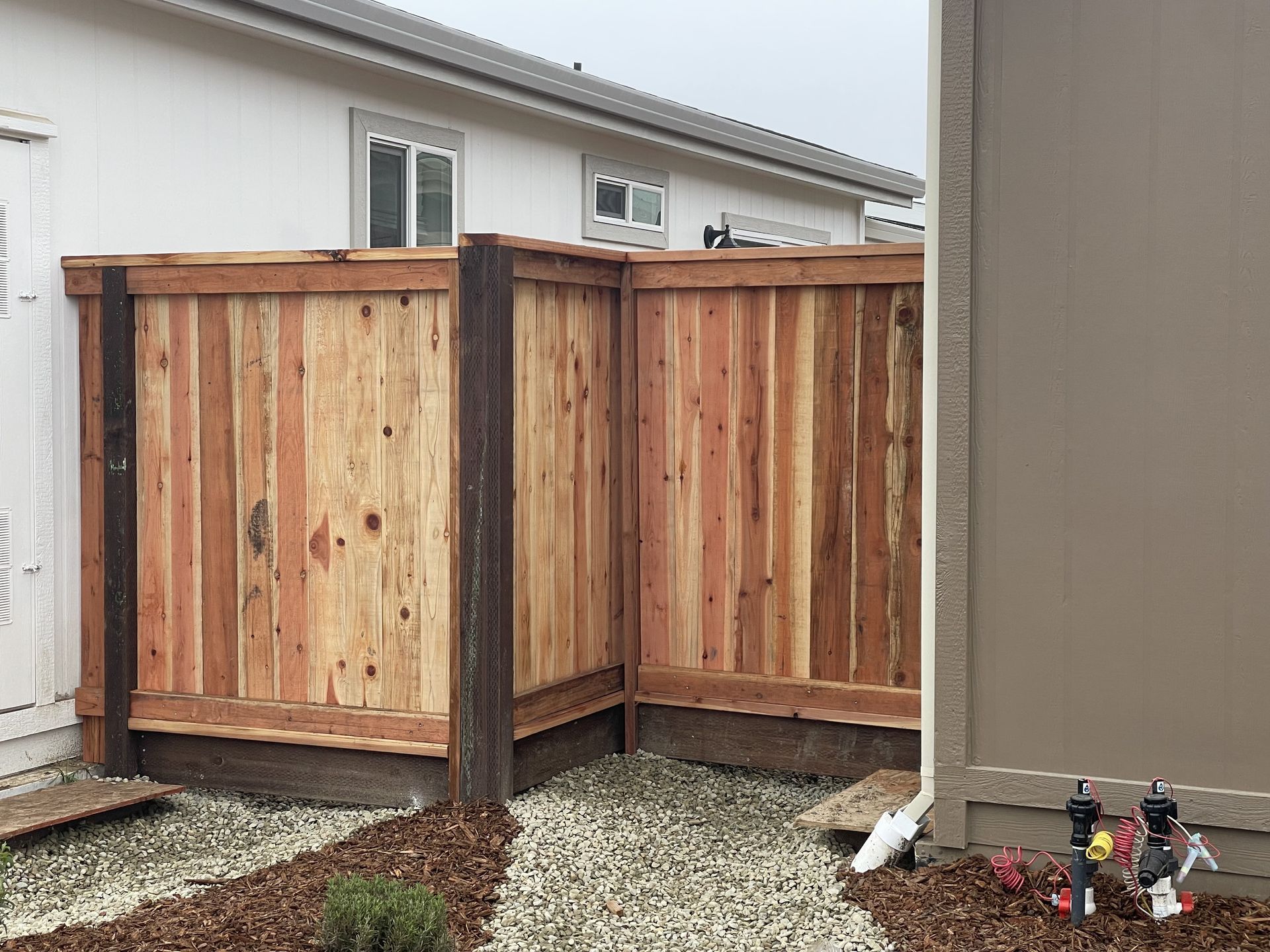 Wooden privacy fence in a yard with gravel and mulch.